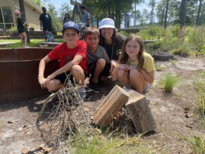 Teen leader with campers outside by fire pit